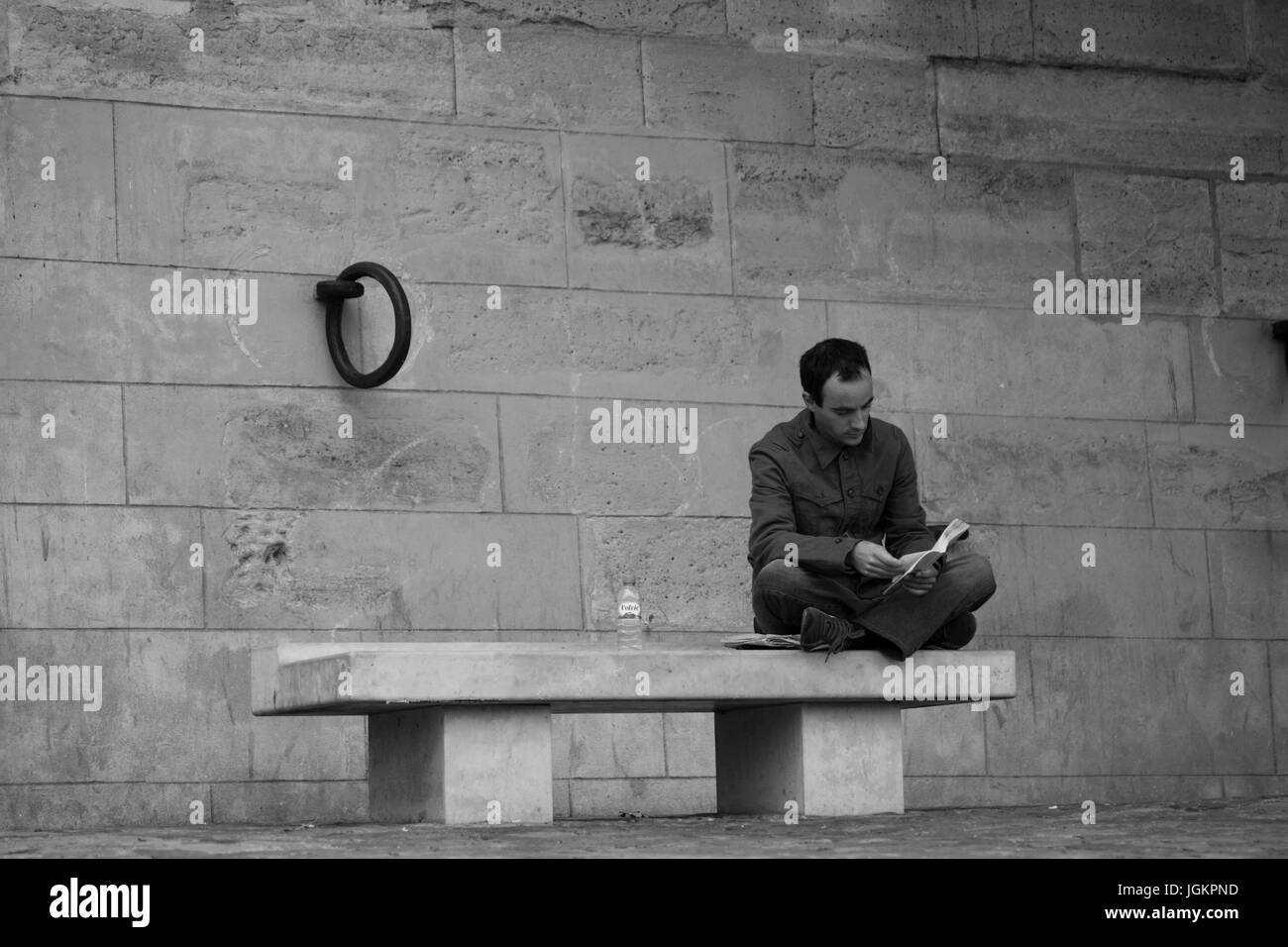 PARIS, FRANCE – 12 AUGUST 2006: A man sitting on a bench on the waterfront of the River Seine and reading a book. 12 August, 2006. Paris, France. Stock Photo