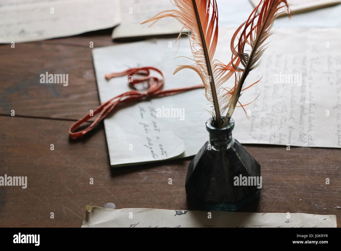 Feather quill pen in inkwell with old documents Stock Photo