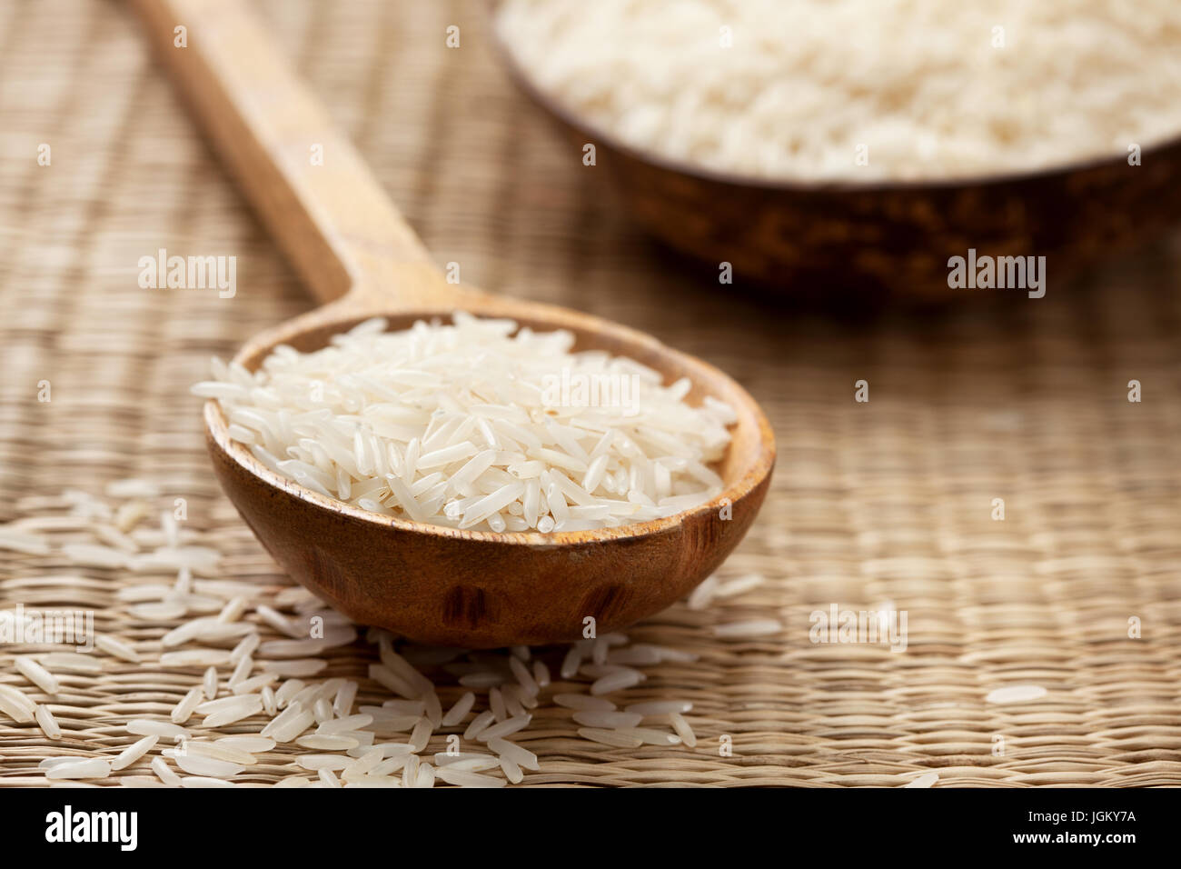 Basmati rice in wooden spoon on straw background Stock Photo