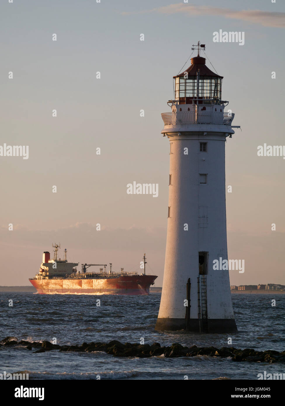Homeward bound. A merchant ship arriving in the Mersey estuary, passing New Brighton lighthouse. Stock Photo