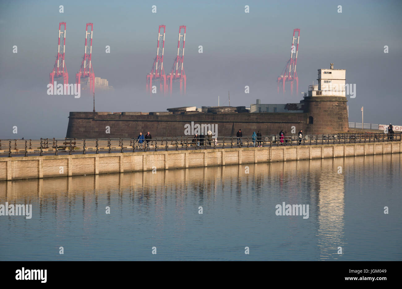 Giant dockside cranes at Seaforth container terminal rising out of the mist behind Fort Perch Rock, New Brighton Stock Photo
