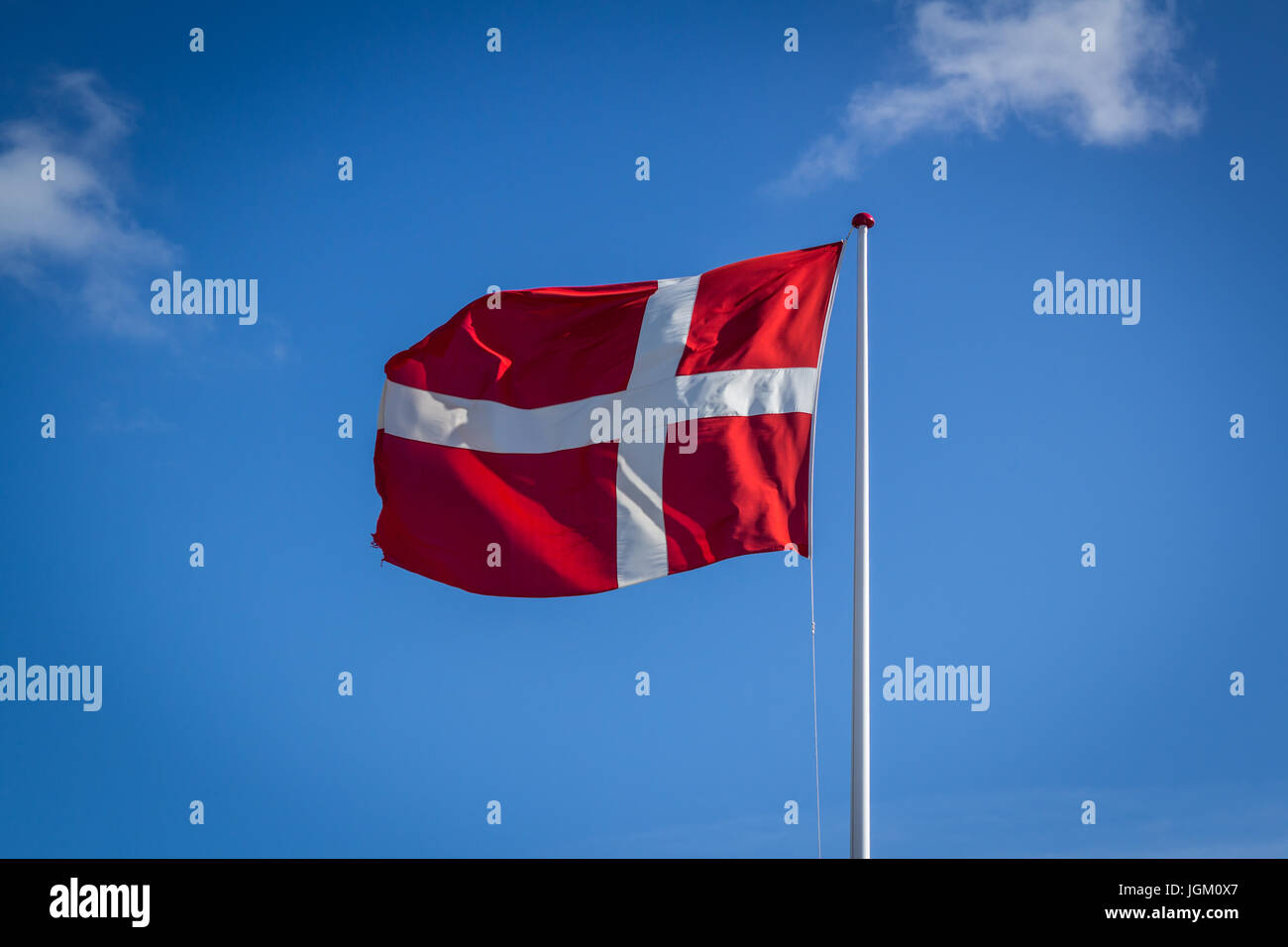 Danish flag in sunshine against blue sky with clouds, horizontal Stock Photo