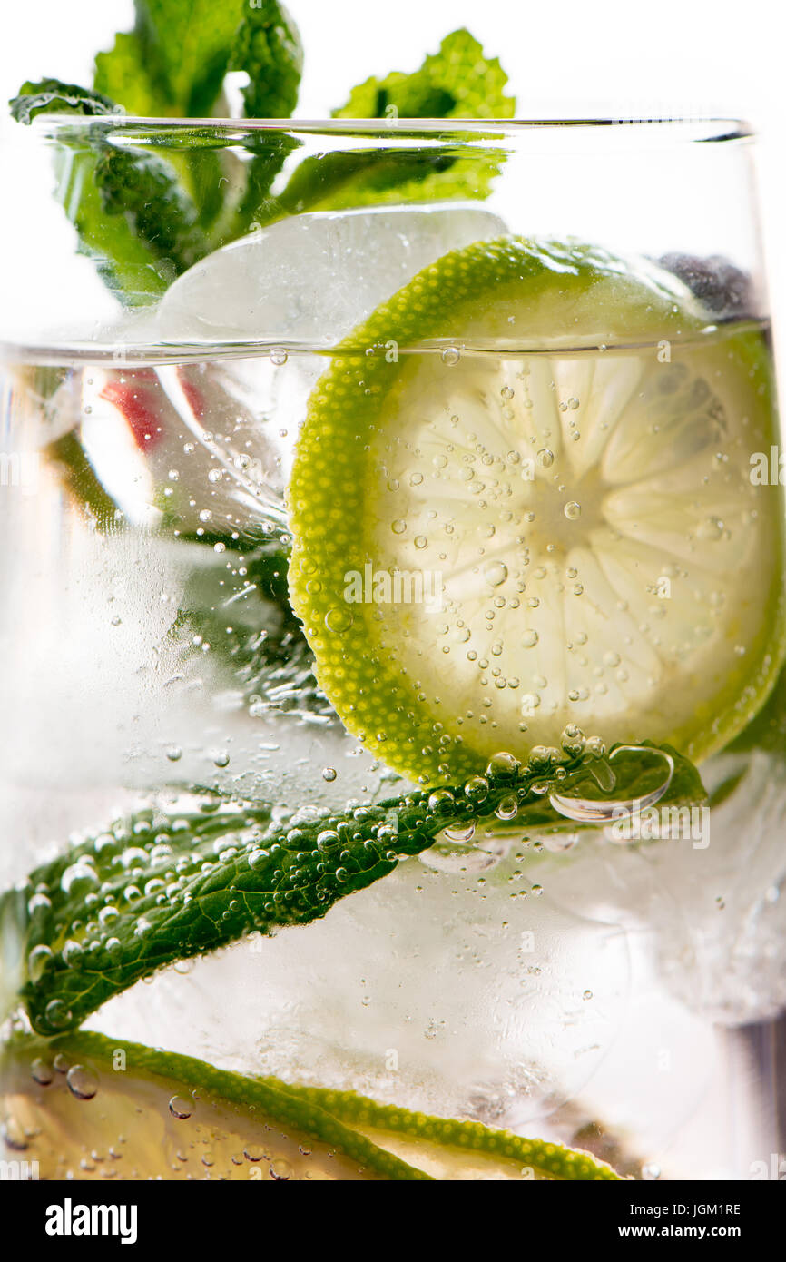 Gin tonic cocktail with lime, lemon ice and mint, white background. Close up detail Stock Photo