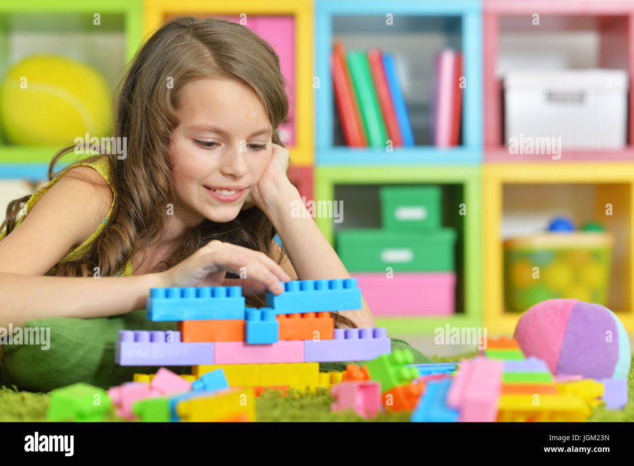 Cute girl playing with colorful plastic blocks Stock Photo - Alamy