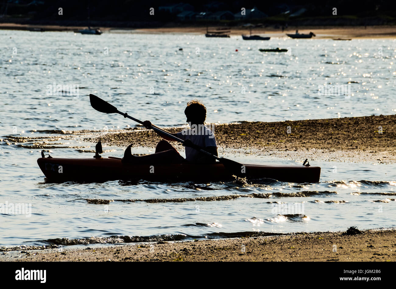 Wellfleet, USA July 30, 2014 Young boy pulling kayak boat from sea in Cape Cod Stock Photo