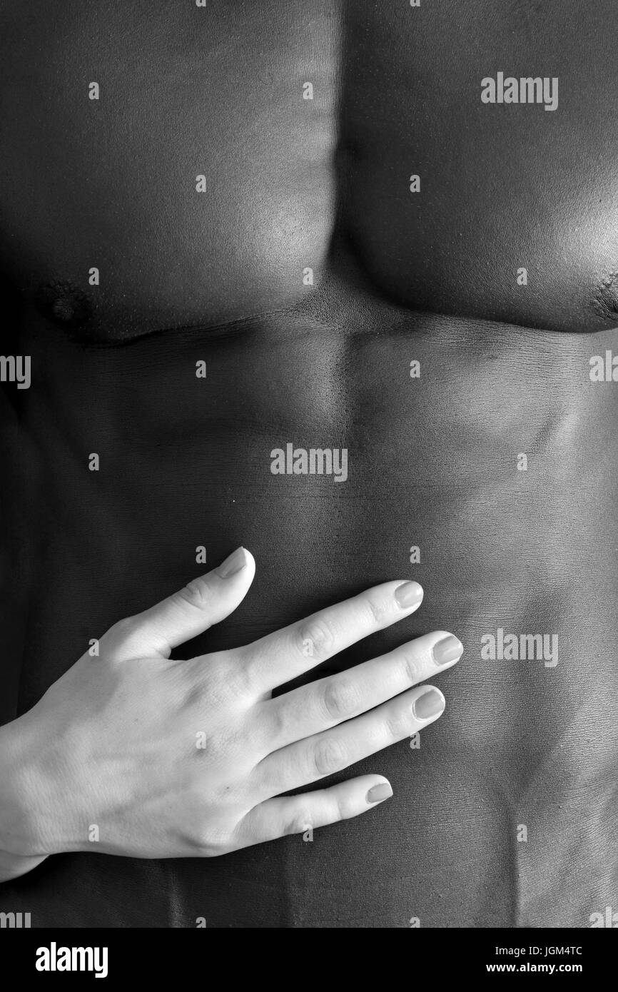 A white woman's hand on a muscular belly of a black man Stock Photo