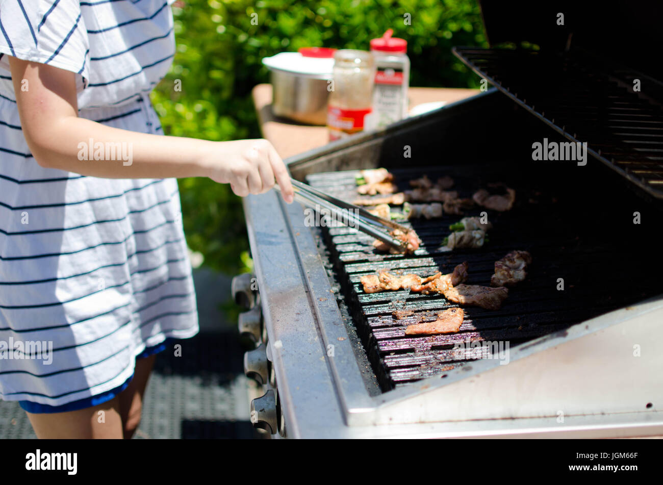 Girl flipping meat with tongs on outdoor bbq grill Stock Photo Alamy