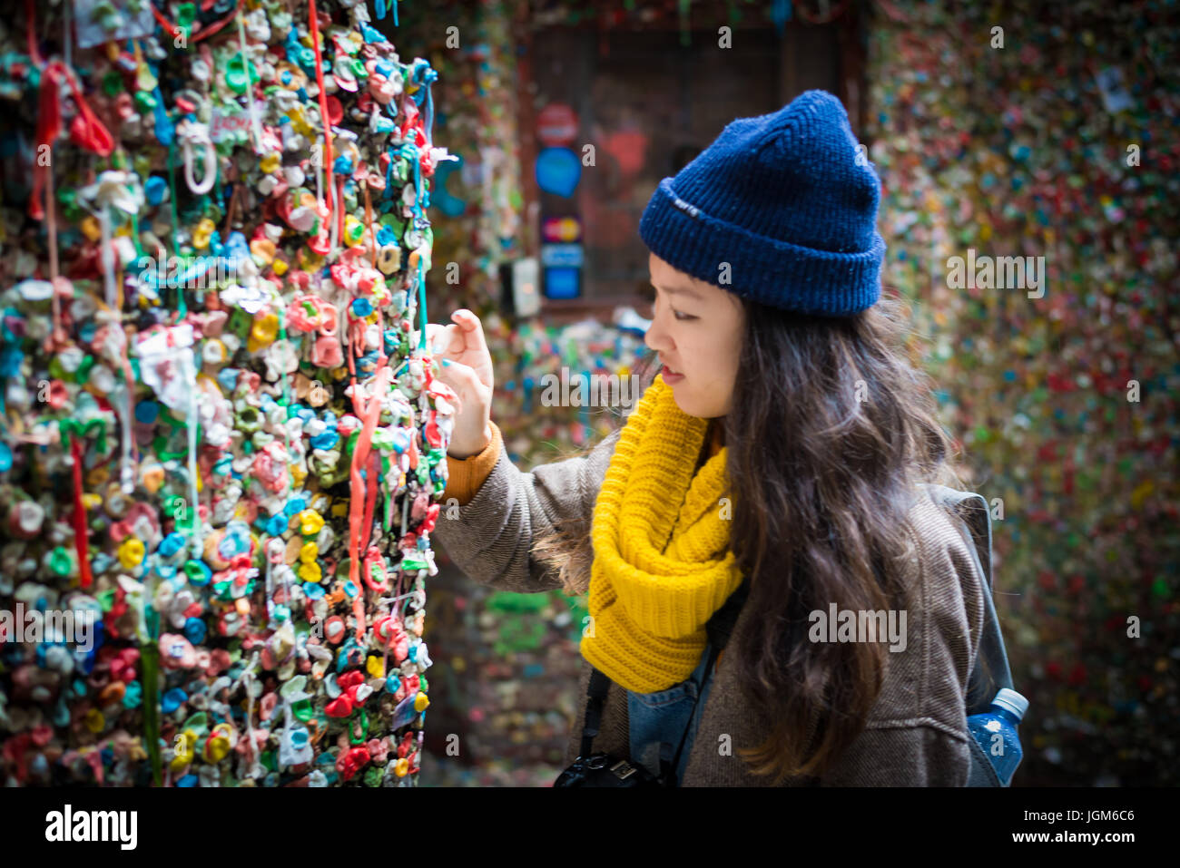 Girl sticking a piece of chewed up bubblegum on Seattle's gum wall. Stock Photo