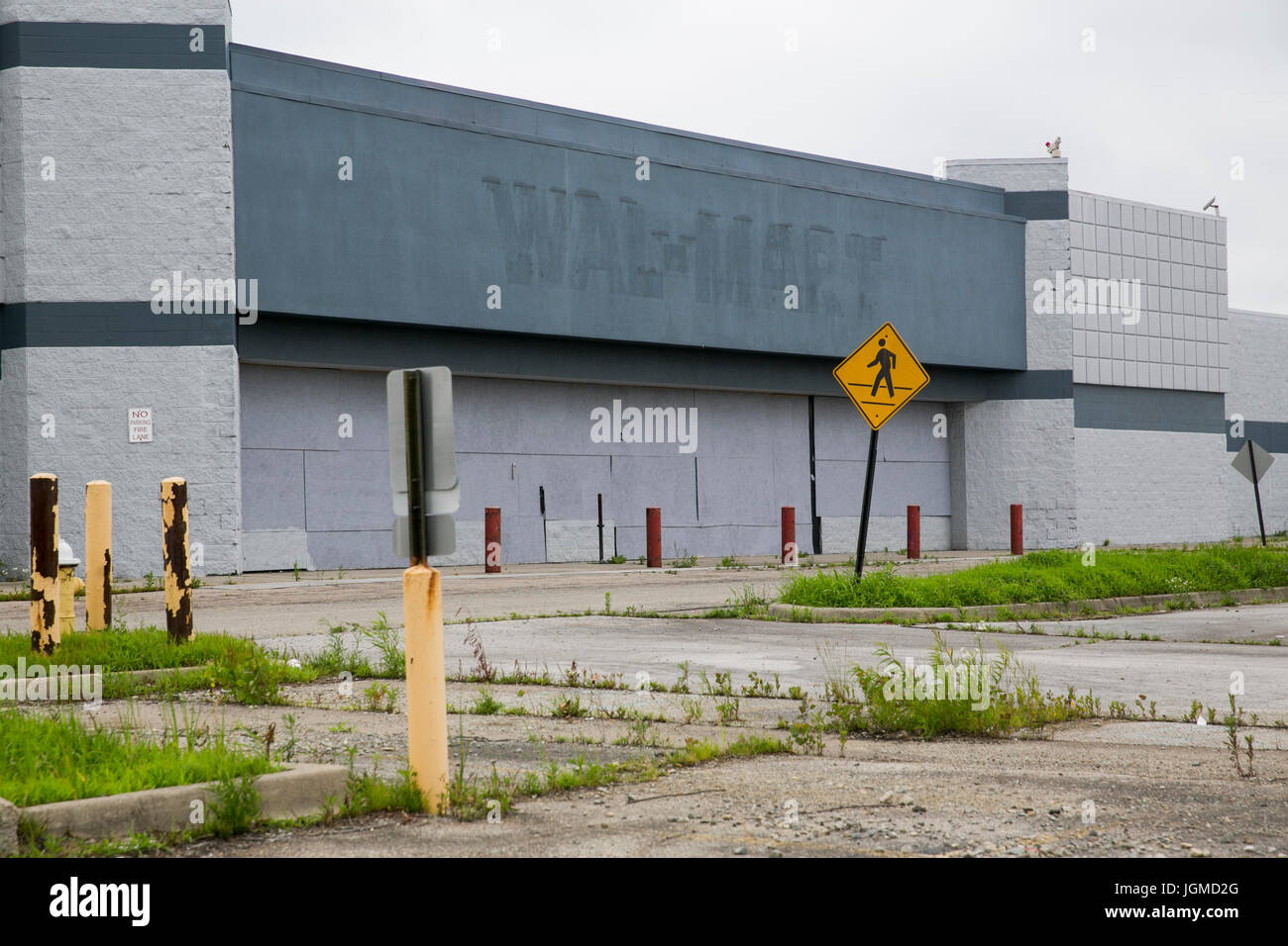 A logo sign outside of a closed and abandoned Walmart retail store in ...