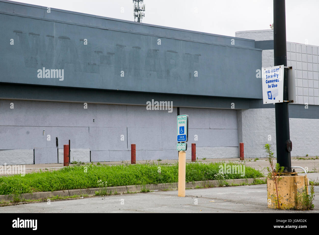 A logo sign outside of a closed and abandoned Walmart retail store in ...