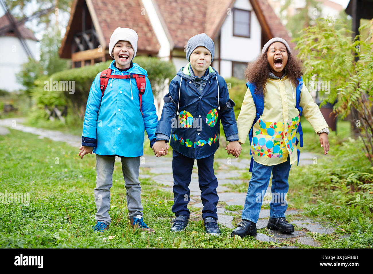 Three happy little schoolkids with backpacks, one of them African ...