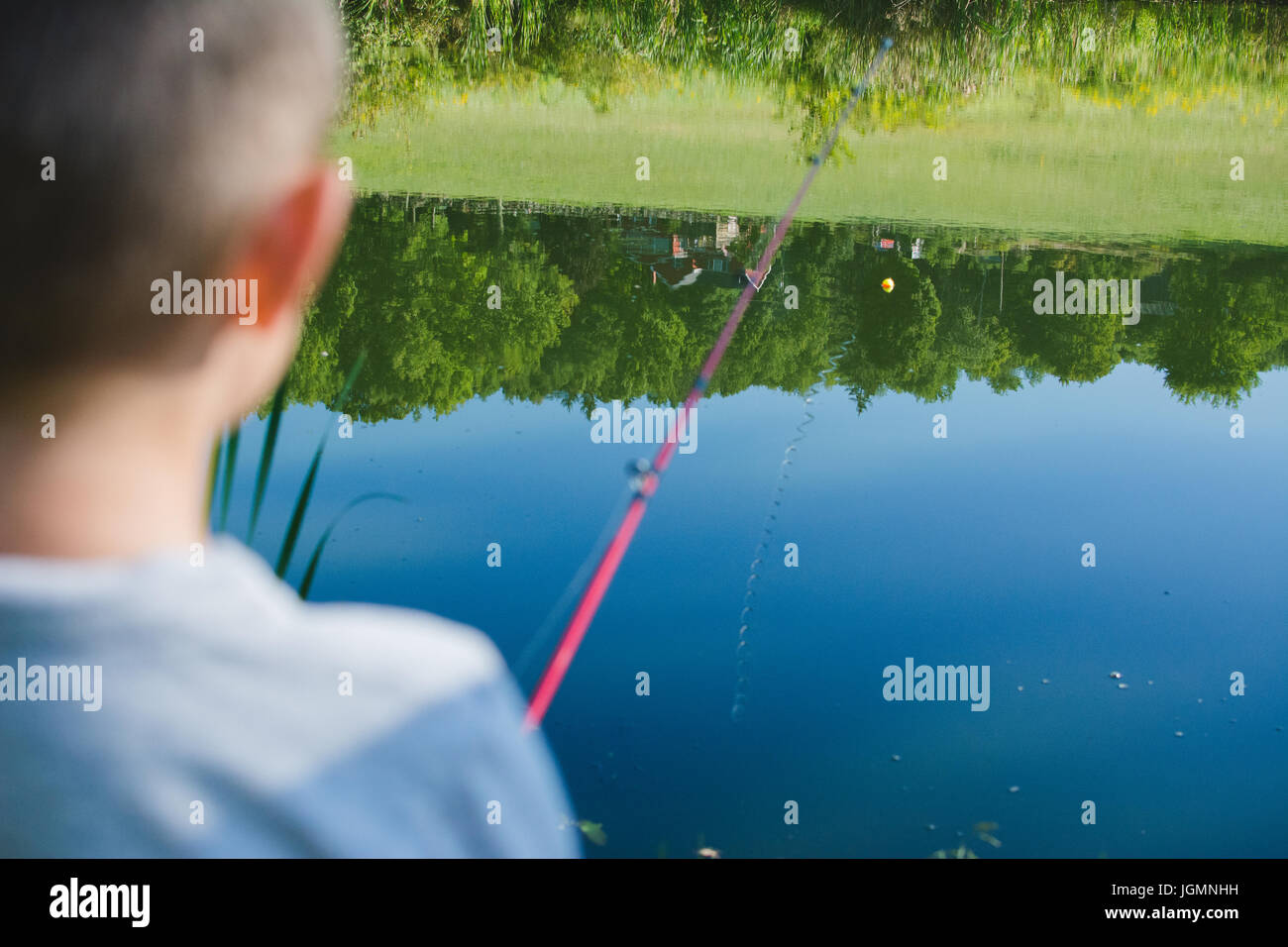 A child fishing at a pond in a rural area. Stock Photo