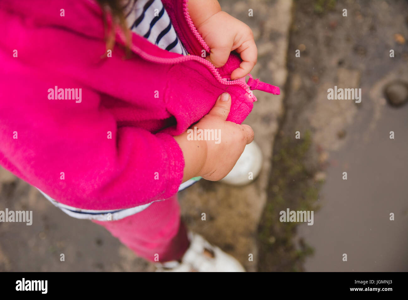 A toddler zipping her jacket hands only. Stock Photo