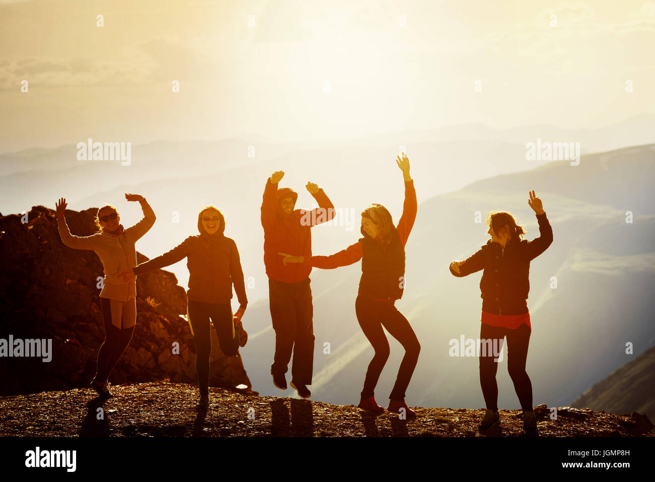 Happy friends dancing on sunset mountain Stock Photo