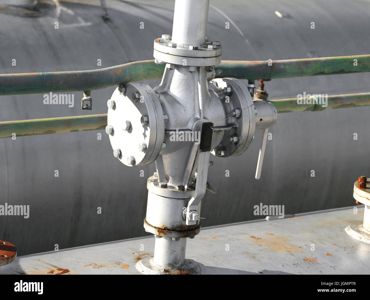 Big shut-off valve above the large fuel tank in the storage area of the industrial plant Stock Photo