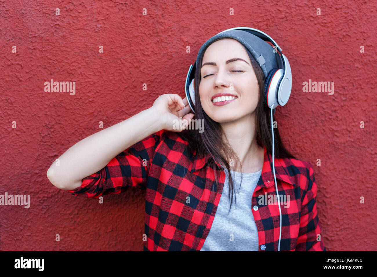 Portrait of happy hipster woman listening music in headphones. Copy space. Technology, music, lifestyle, and millenial people concept Stock Photo