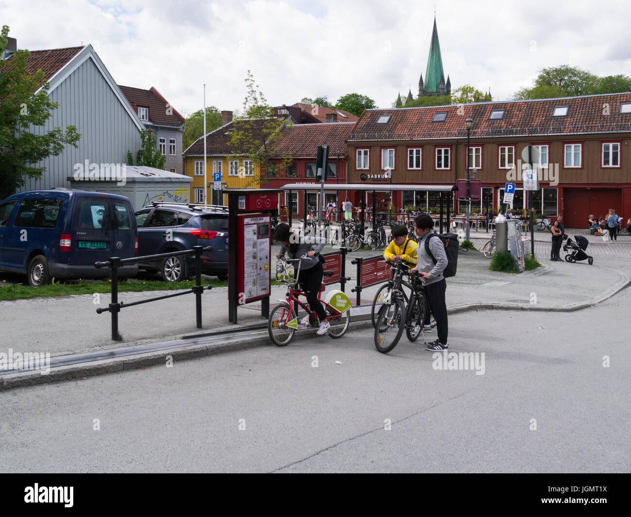 A girl and two young men on bicycles looking to use the Trampe bicycle lift in Trondheim to go up steep hill at Brubakken near Gamle Bybro Norway Stock Photo