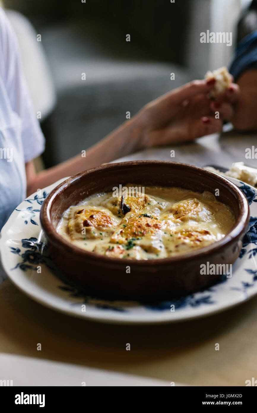 Person eating ravioli with gratin cheese, on the antique plate in ...