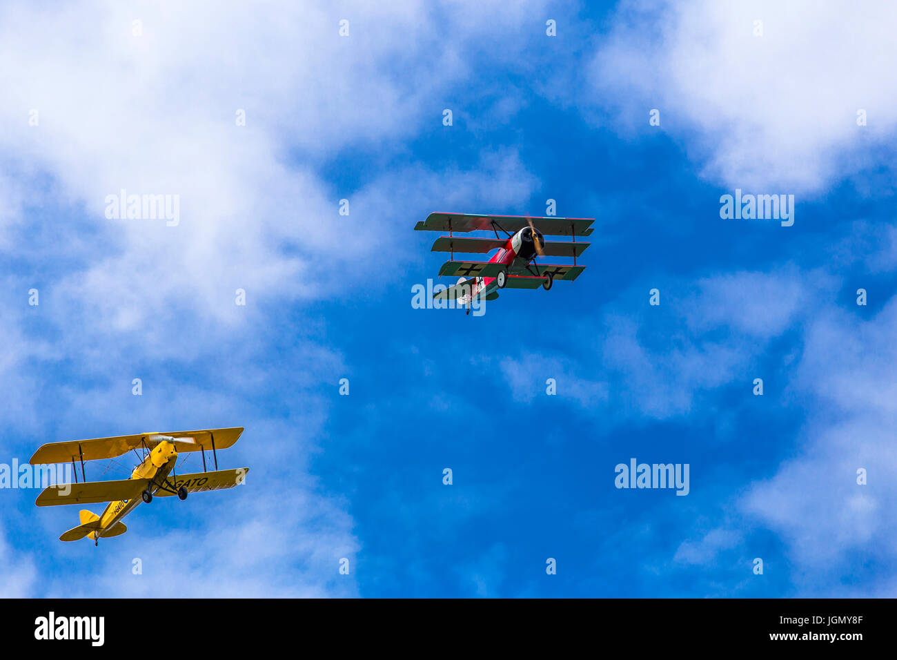 Flying triplane Fokker Dr-1 M and biplane Tiger Moth I-GATO replicas next to each other between the clouds. Stock Photo