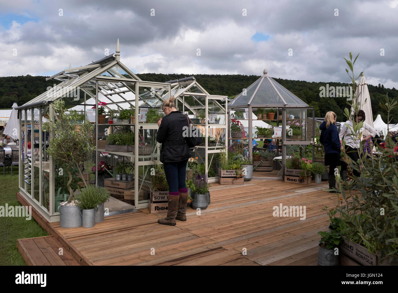 Lady closely inspecting greenhouses on display & for sale at Rhino tradestand - RHS Chatsworth Flower Show, Chatsworth House, Derbyshire, England, UK. Stock Photo