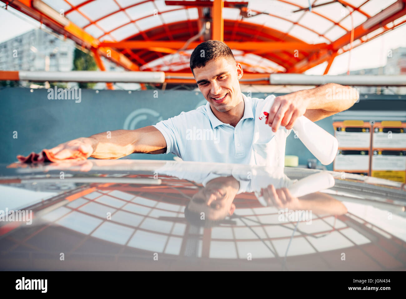 Man rubbing vehicle with car polish after washing. Automobile polishing
