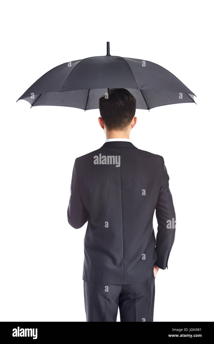 rear view of a young asian businessman in formal wear holding an umbrella with one hand in pocket, isolated on white background. Stock Photo