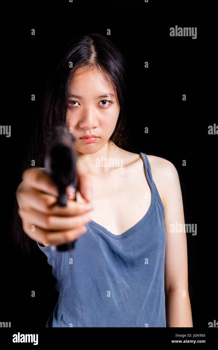 Teenage Asian American girl pointing handgun Stock Photo