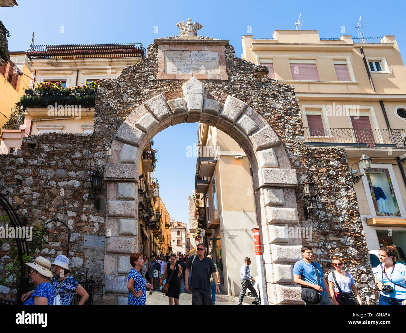 TAORMINA, ITALY - JUNE 29, 2017: tourists walk through old gateway Porta Messina in Taormina city. Taormina is resort town on Ionian Sea in Sicily Stock Photo