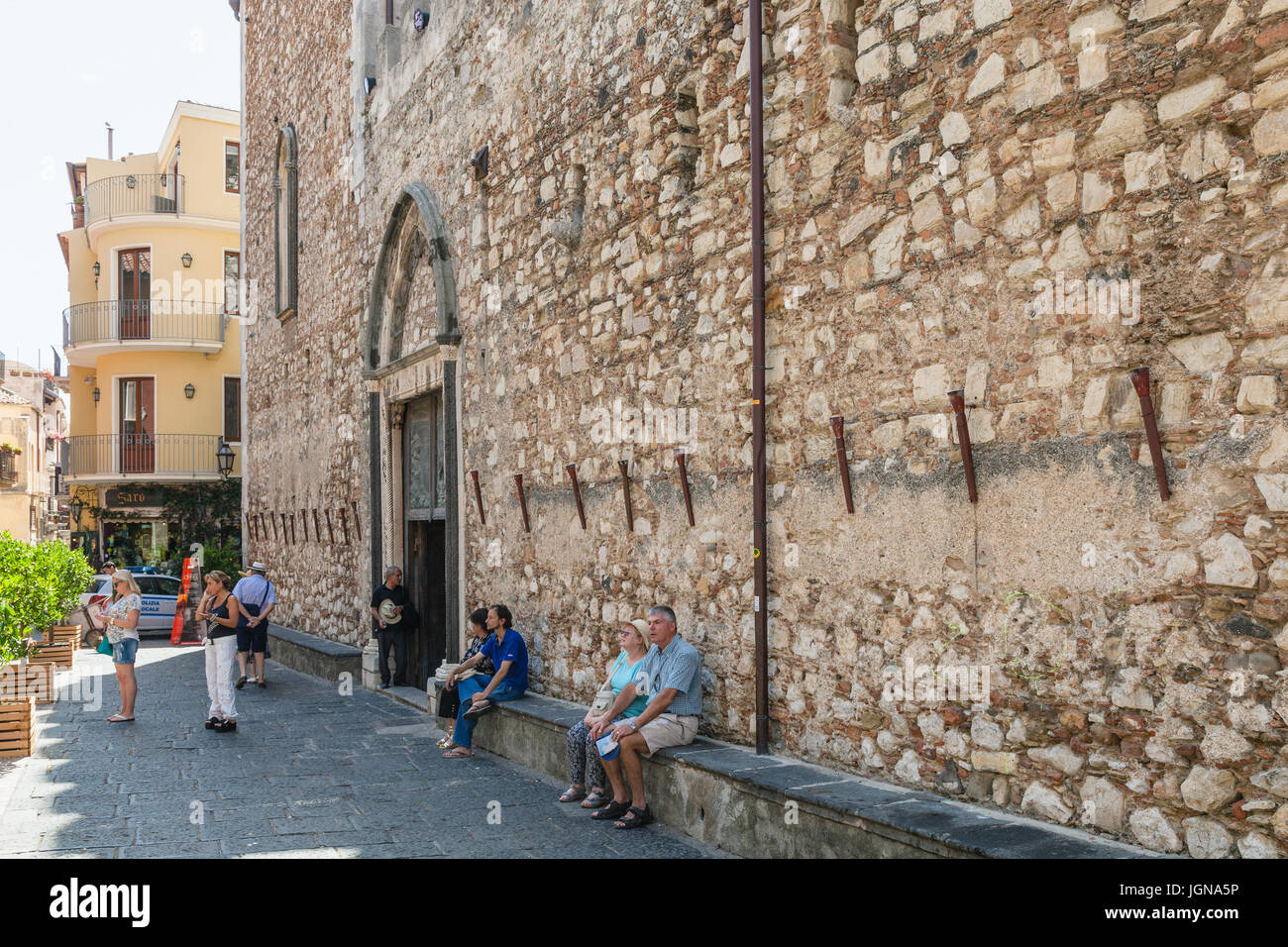 TAORMINA, ITALY - JUNE 29, 2017: visitors near wall of Duomo di Taormina (Cathedral San Nicolo di Bari) in city. Taormina is resort town on Ionian Sea Stock Photo