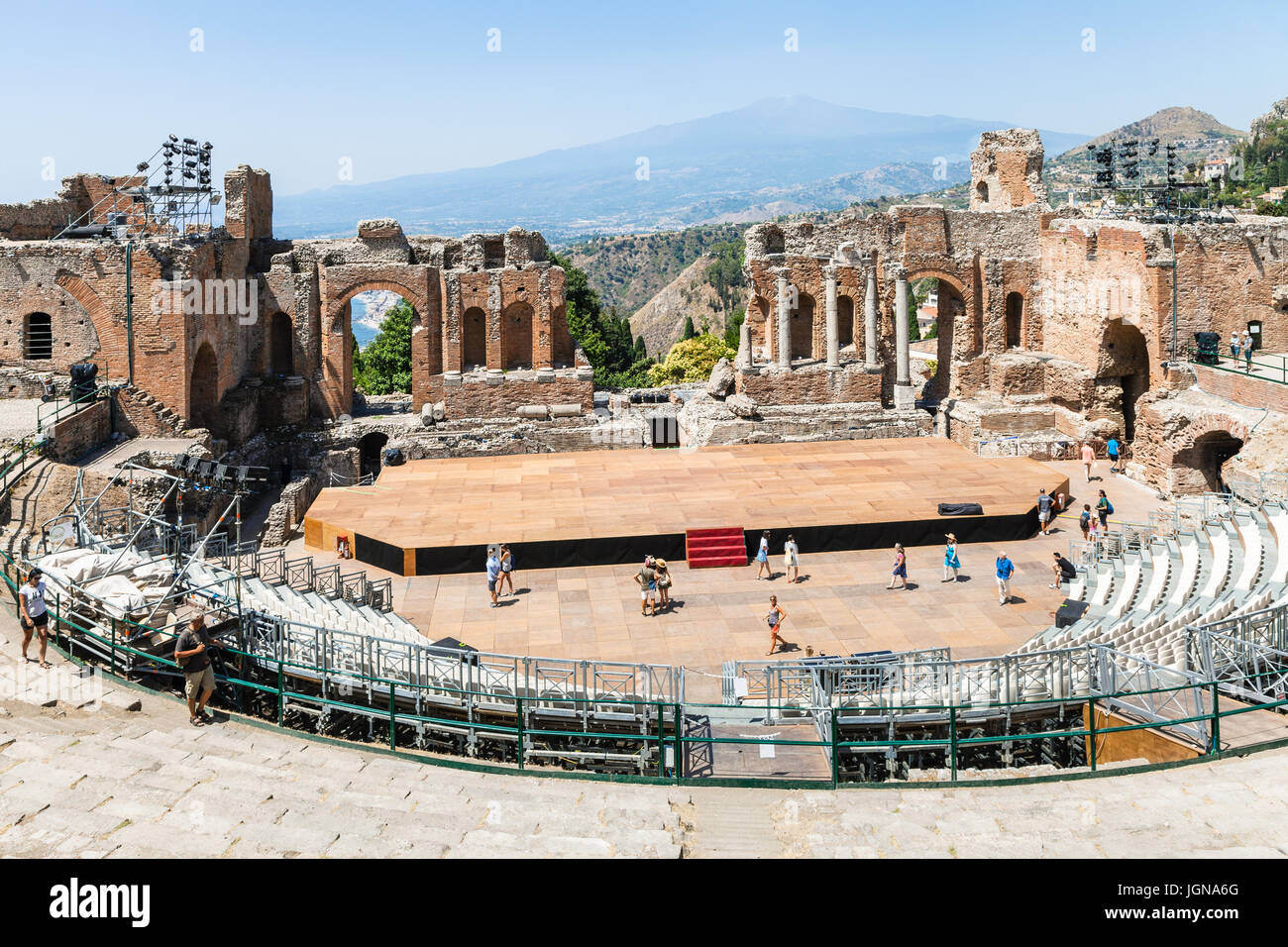 TAORMINA, ITALY - JUNE 29, 2017: tourists in Teatro antico di Taormina, ancient Greek Theater (Teatro Greco) and view of Etna mount in summer day. The Stock Photo