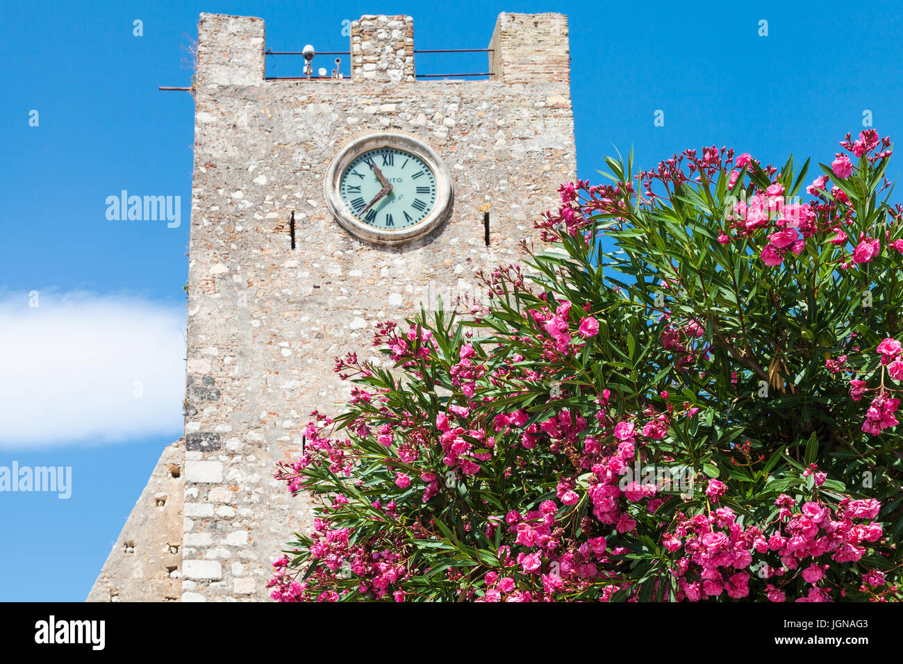 travel to Sicily, Italy - oleander tree and medieval clock tower (Torre dell Orologio) at Piazza IX Aprile in Taormina city in summer day Stock Photo