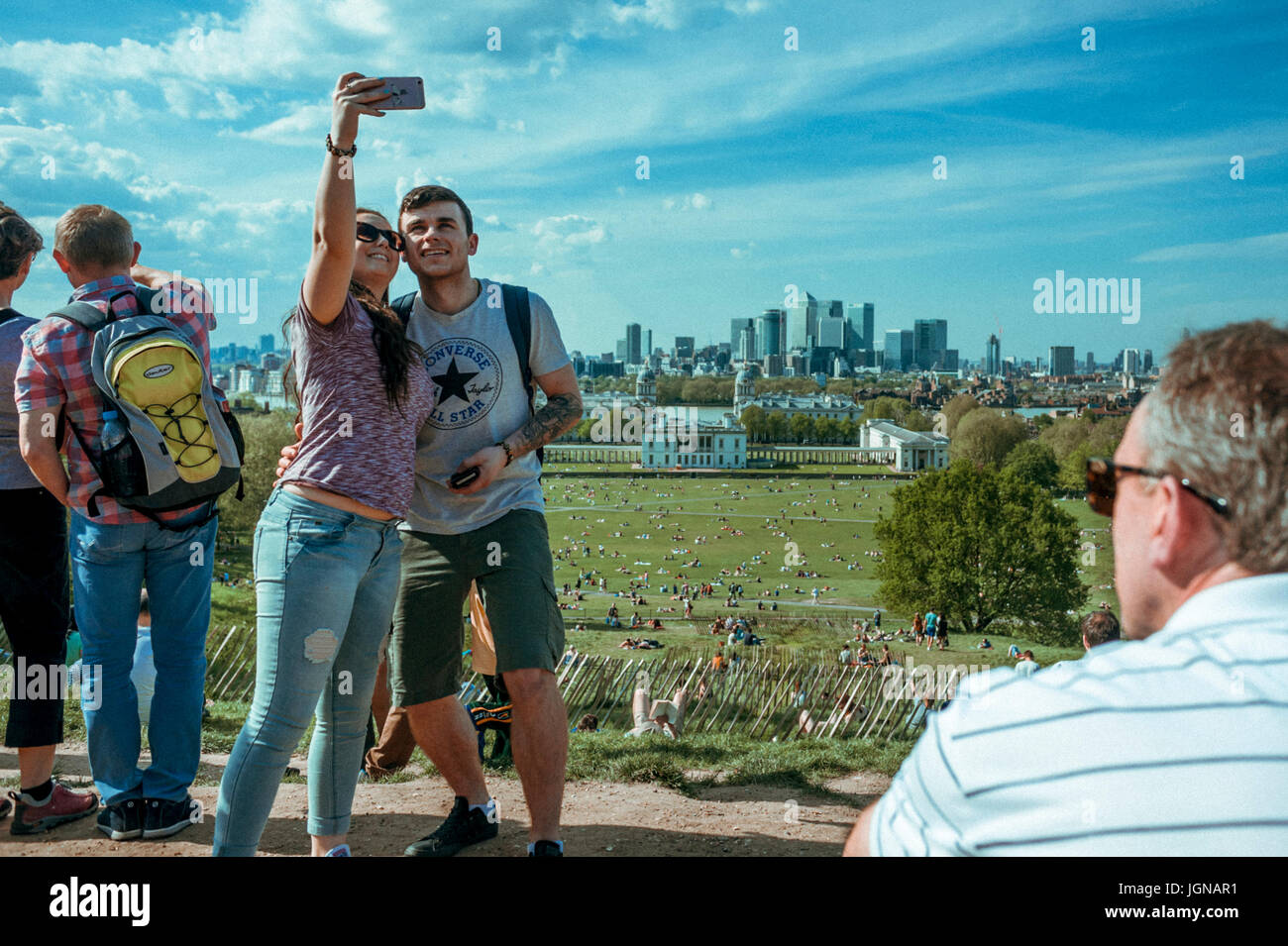 Young couple is taking a selfie with Canary wharf in the background. Stock Photo