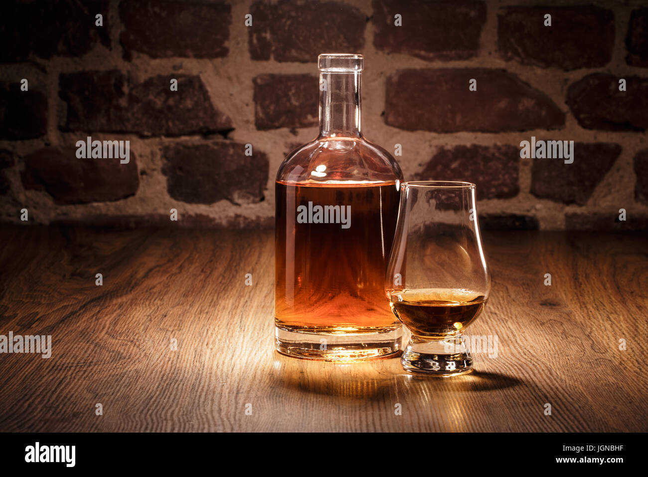 Bottle of whiskey with nosing glas in front of an old stonewall Stock Photo