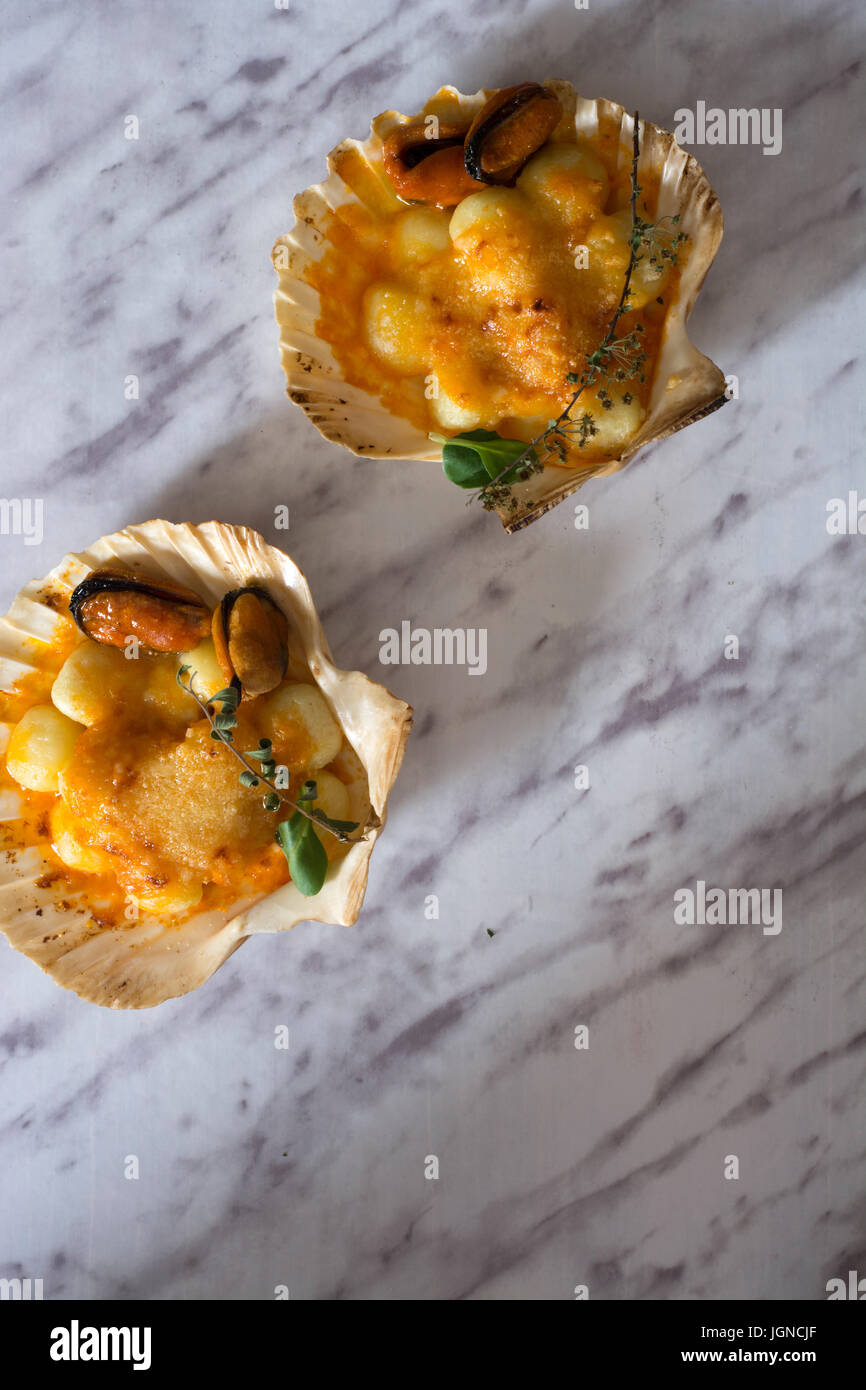 Gnocchi pasta with mussels, tomato and cream room, in vieira shell