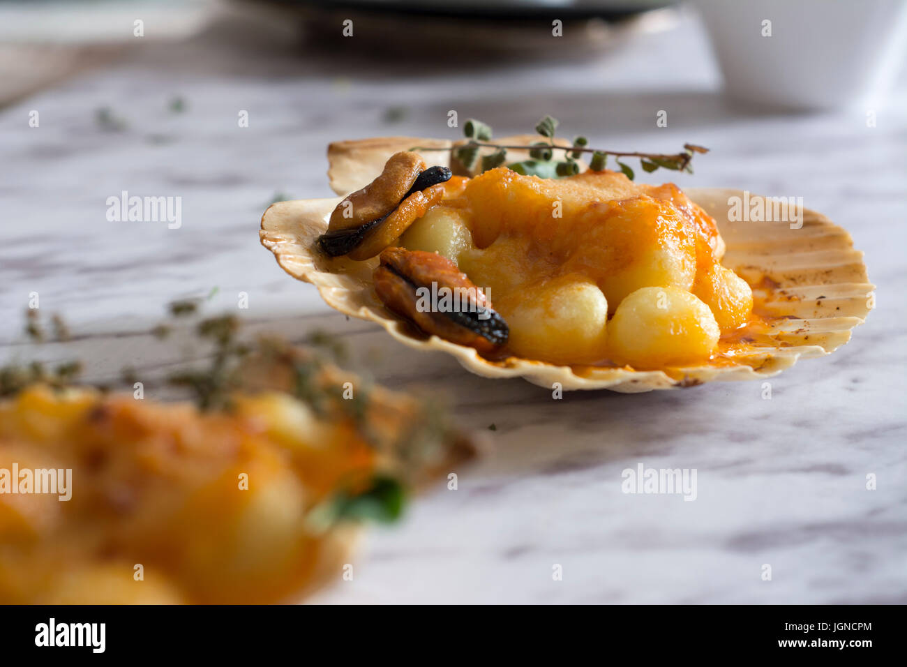 Gnocchi pasta with mussels, tomato and cream room, in vieira shell Stock Photo