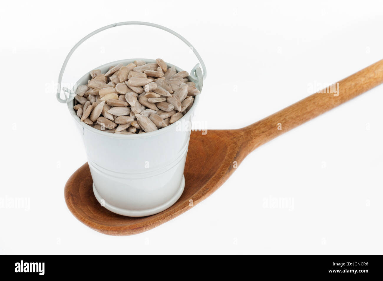 Full bucket of sunflower seeds stands in a wooden spoon. The concept of