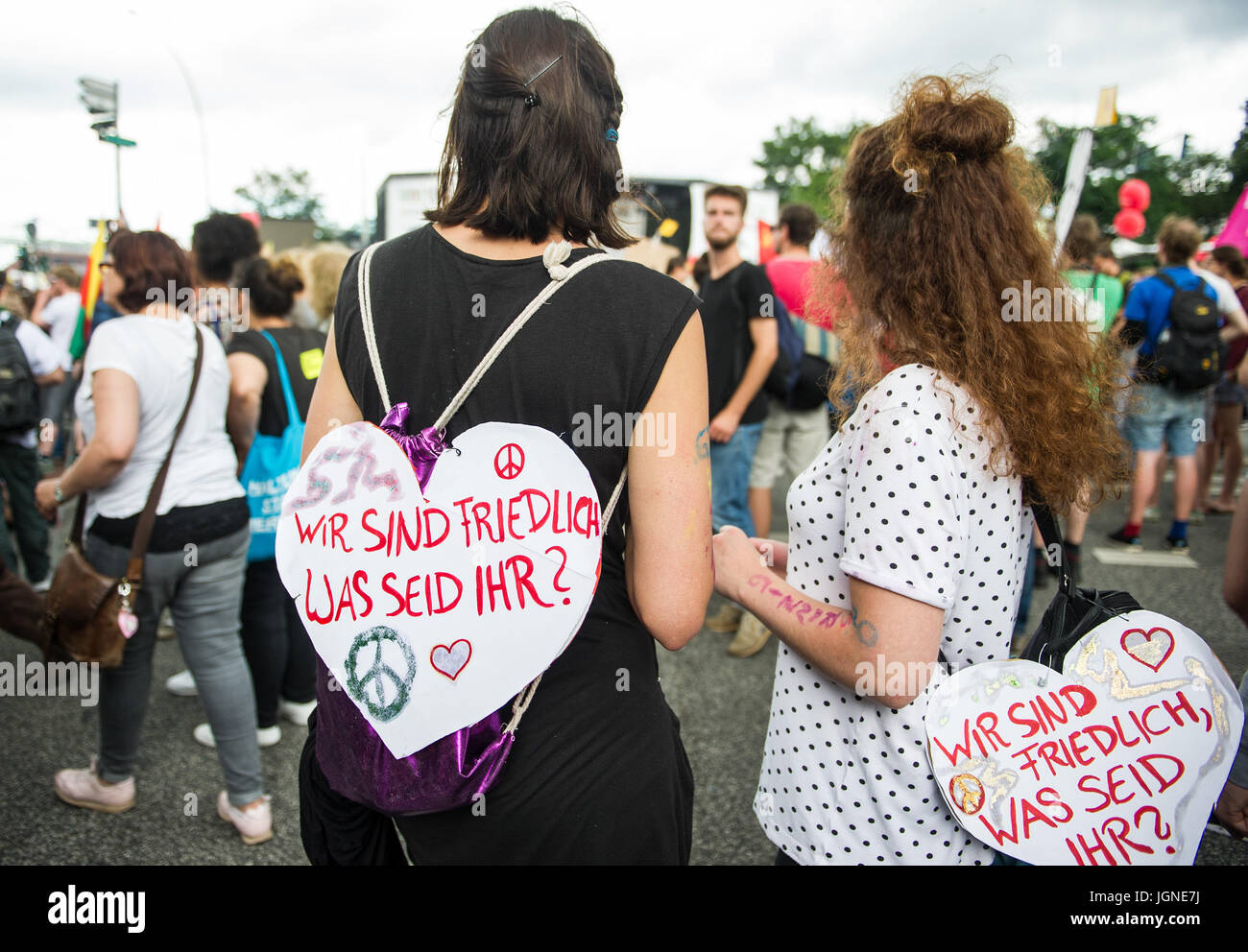 Hamburg, Germany. 8th July, 2017. Two demonstrators carry signs reading 'Wir sind friedlich was seid ihr?' (lit. 'We are peaceful what are you?') during the 'Grenzenlose Solidaritaet statt G20' demonstration (lit. 'Borderless solidarity instead of G20') in Hamburg, Germany, 8 July 2017. The two-day summit, a meeting of the leaders of the twenty largest world economies as well as representatives of a variety of international institutions, concludes today. Photo: Christina Sabrowsky/dpa/Alamy Live News Stock Photo
