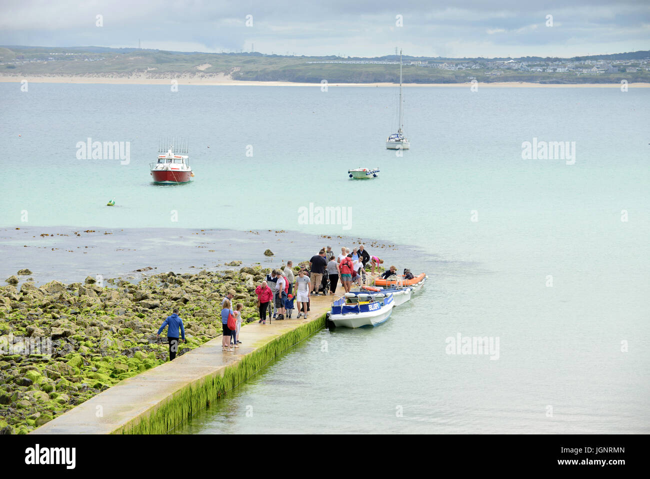 People standing on a jetty on the beach waiting for a boat trip in St Ives, Cornwall, England. Stock Photo