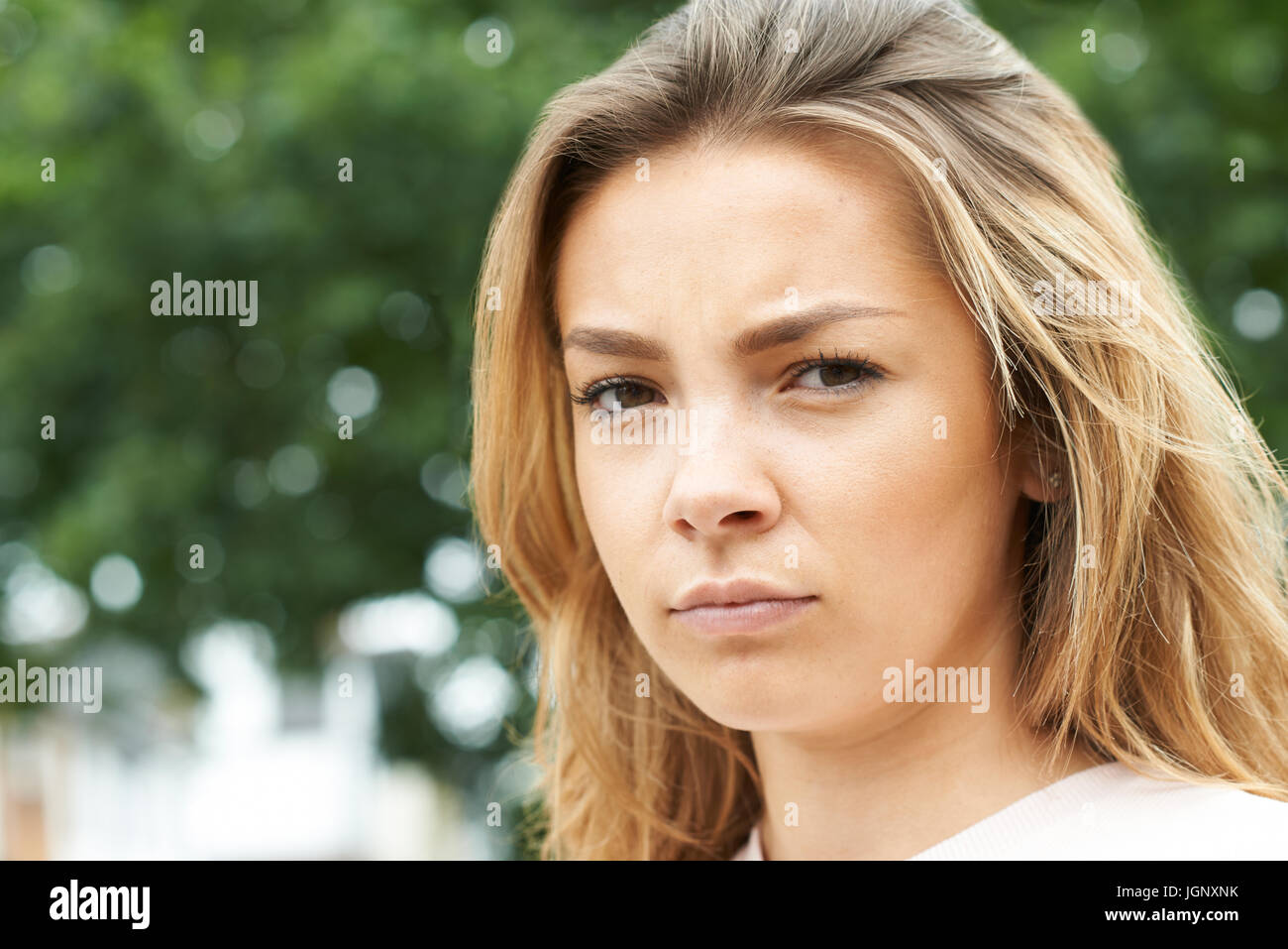 Outdoor Head And Shoulders Portrait Of Serious Teenage Girl Stock Photo