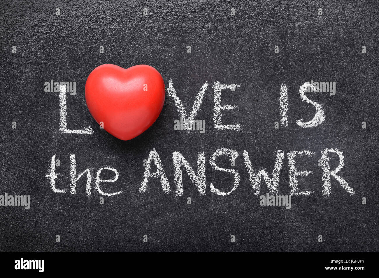 love is the answer phrase handwritten on blackboard with heart symbol instead of O Stock Photo