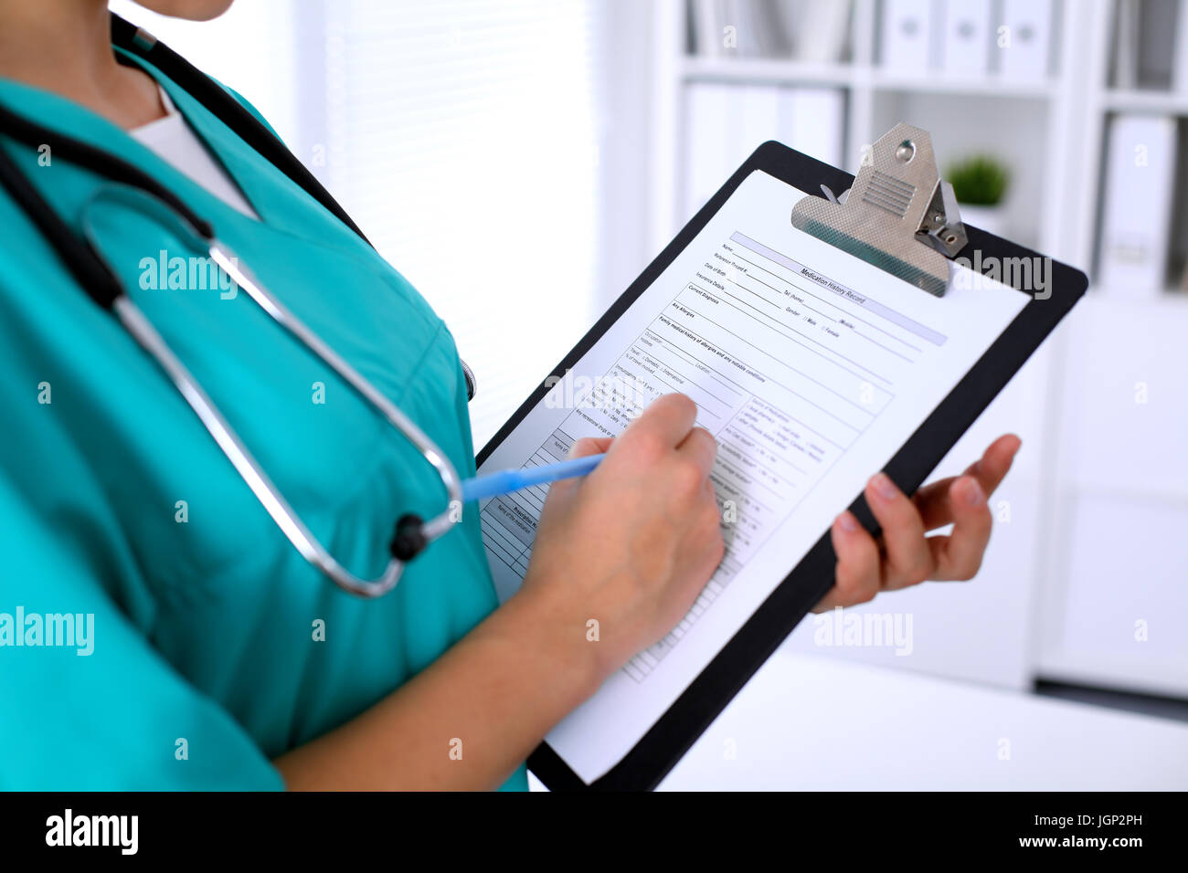 Close-up of a female doctor is filling out application form or medical ...