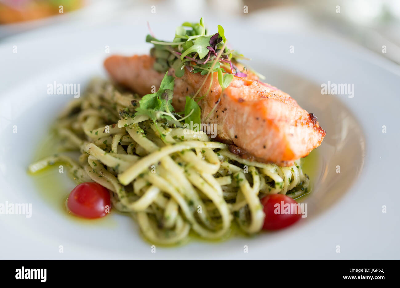 Pesto spaghetti with salmon on top Stock Photo