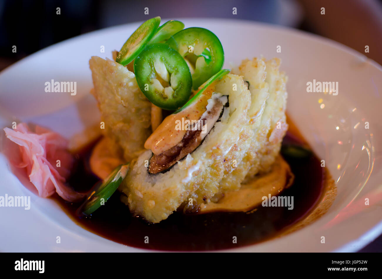 Fried spicy tuna cream cheese roll on a plate with sauce. Stock Photo