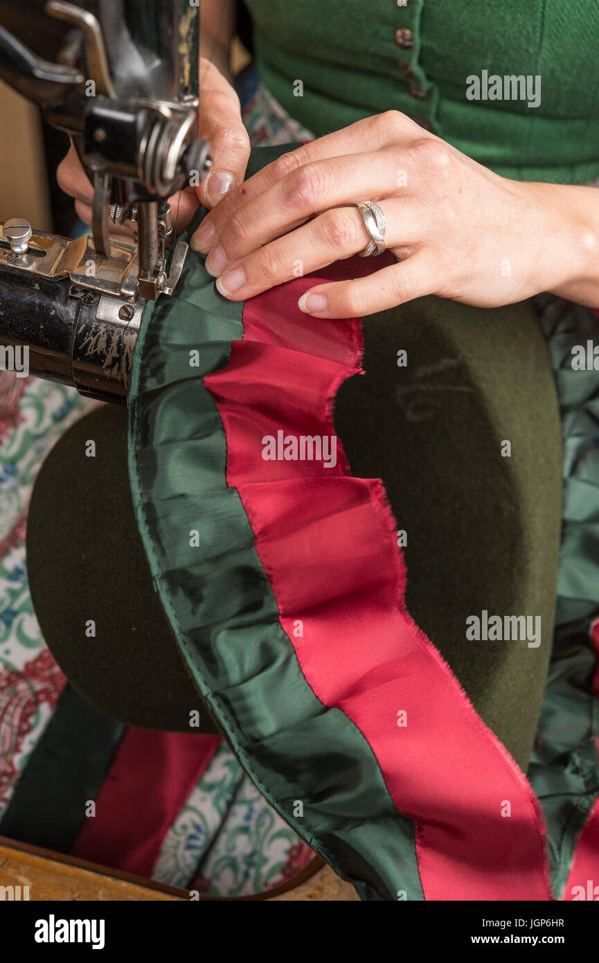 Hands sewing inner lining on a wool felt hat, sewing machine, hatmaker