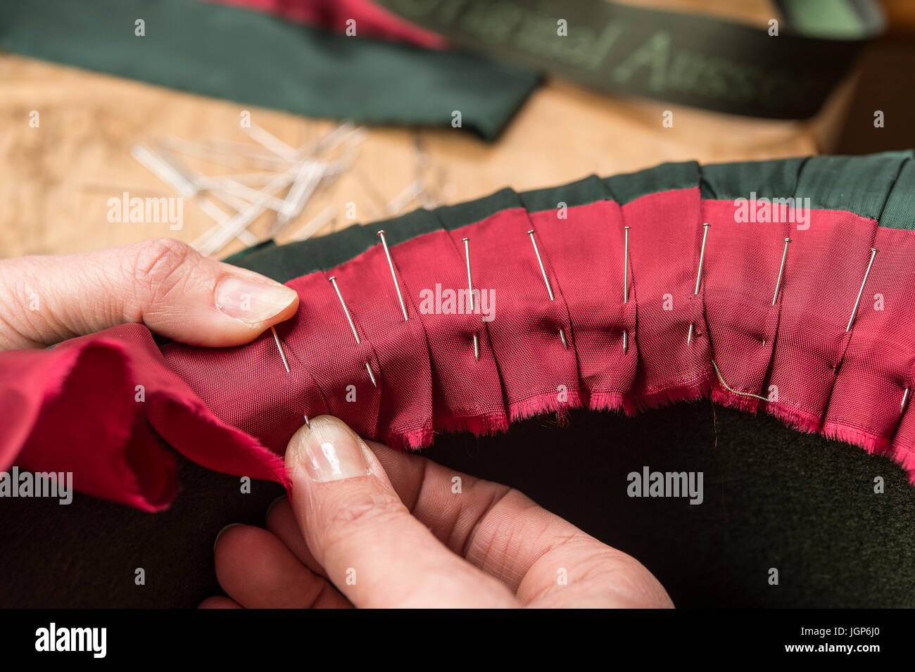 Hands folding and fastening silk ribbon using pins, inner lining of a wool felt hat, hatmaker workshop, Bad Aussee, Styria Stock Photo