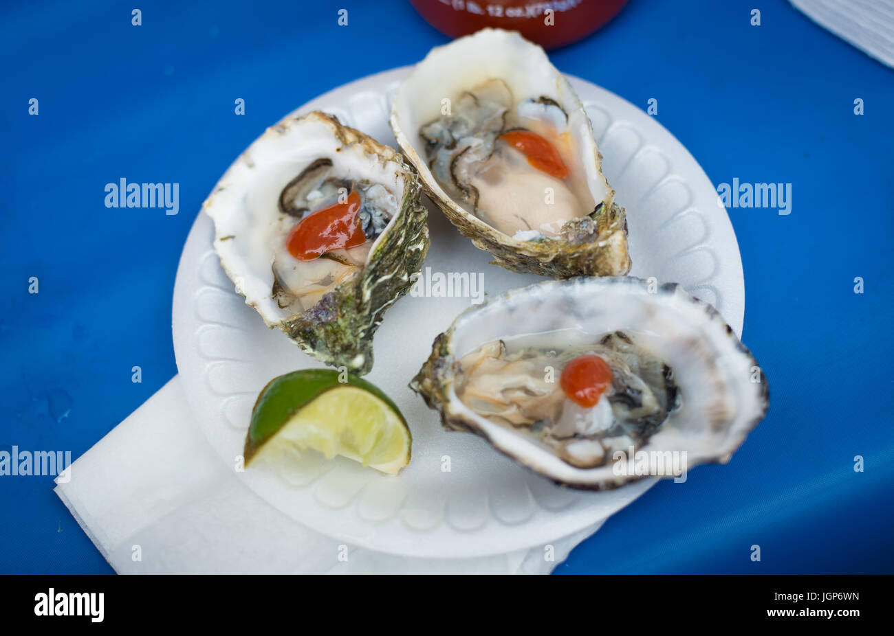 3 fresh shucked oysters on a paper plate with a lime Stock Photo