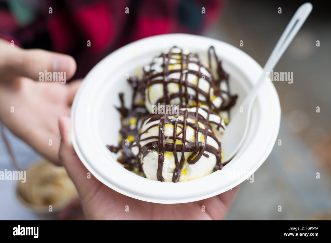 Hand holding an ice cream sundae covered in olive oil and chocolate