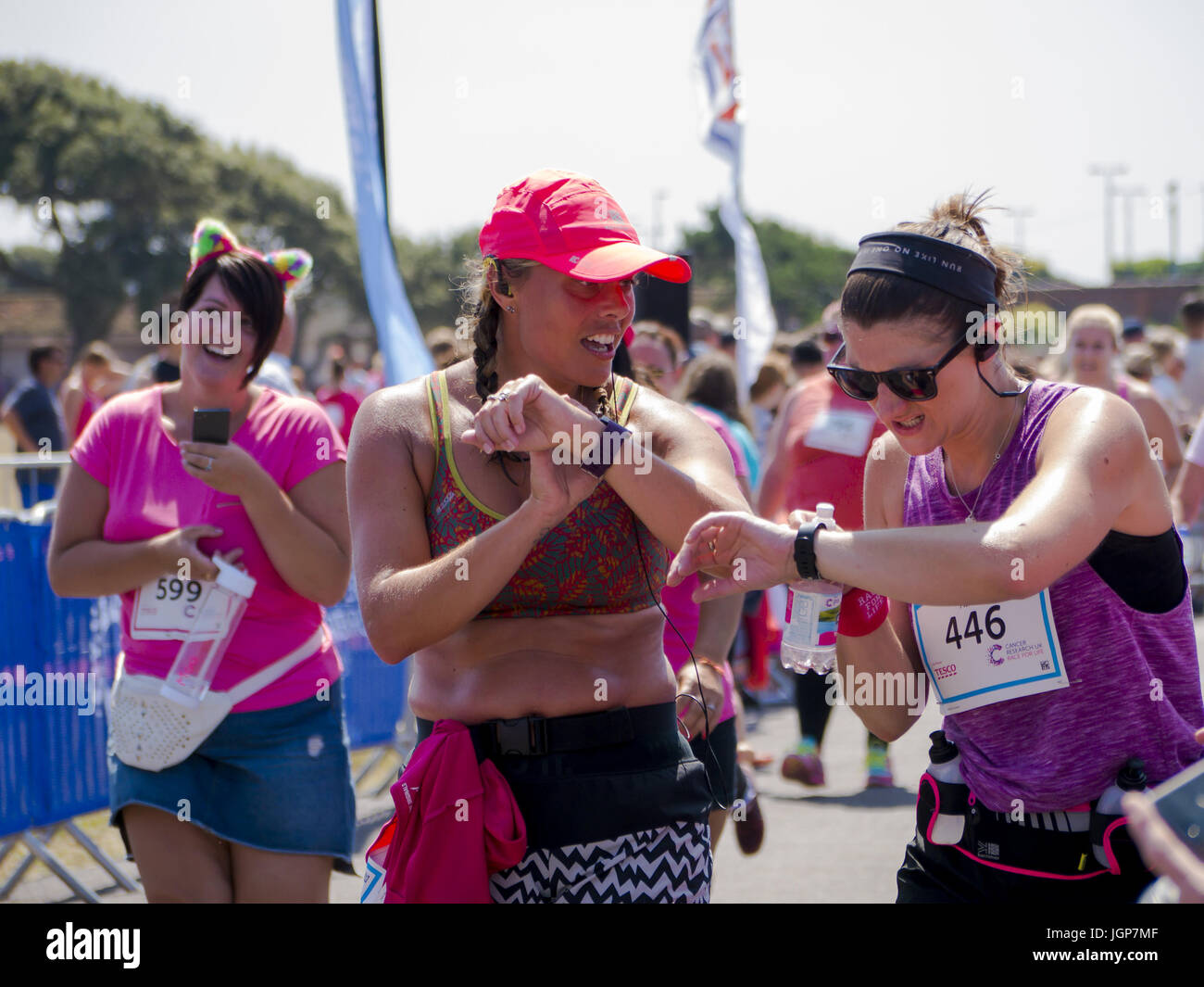 Two ladies check their smart watch GPS timers at the end of a charity fun run. Stock Photo