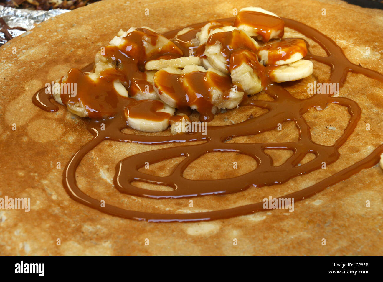 French crepes with bananas and chocolate syrup prepared on grill during Bastille Day street fair Stock Photo