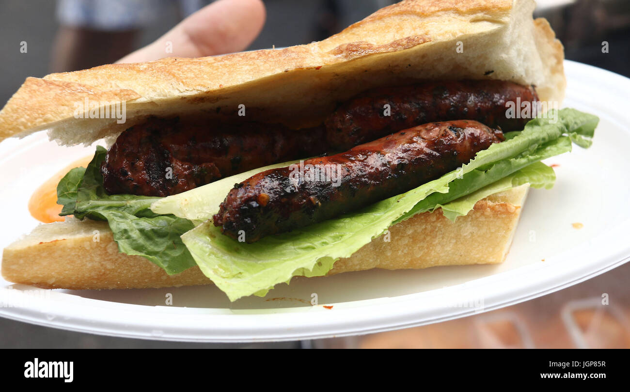 Spicy Merguez, which is a North African lamb sausage, on a baguette with lettuce seen at a Bastille Day street fair in NYC Stock Photo